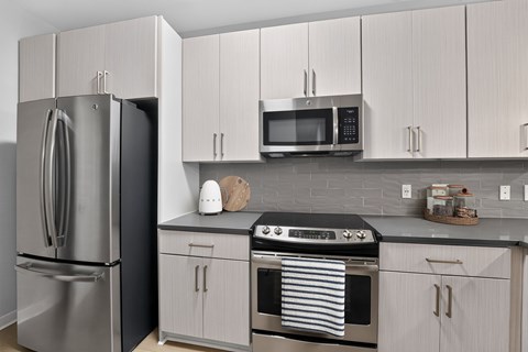 A modern kitchen with a stainless steel refrigerator, microwave, and oven.
