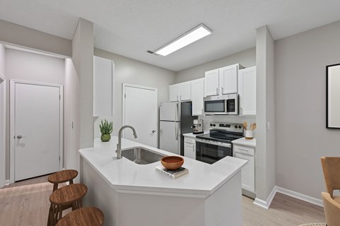 A kitchen with white cabinets and appliances, a sink, and a counter with a bowl and a book on it.