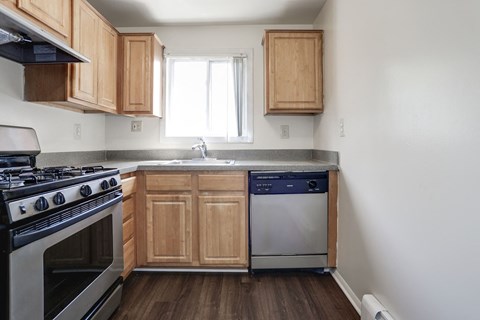 A kitchen with a stove, dishwasher and wooden cabinets.