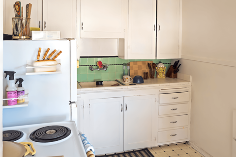 A kitchen with white cabinets and a blue refrigerator.