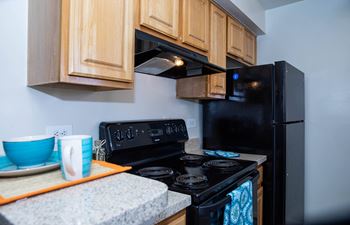 an updated kitchen with black appliances and wood cabinets