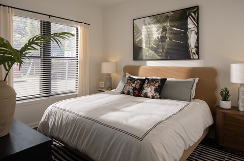 A bedroom with a large bed and a painting on the wall.