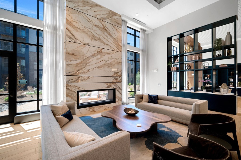 a living room with couches and a fireplace and a marble wall at Preston Ridge, Cary