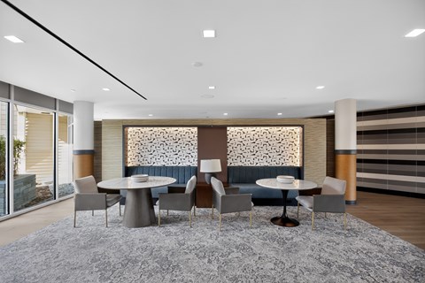 A modern dining room with a grey rug and a round table with chairs.