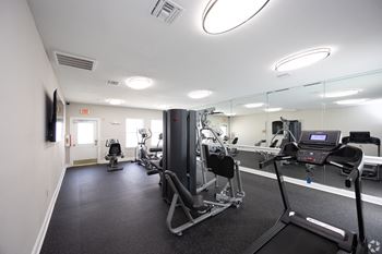 a gym with exercise equipment and mirrors in a building at Magnolia Pointe Apartments in Duluth, GA