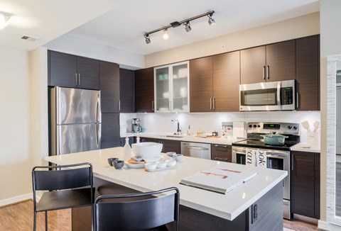 a kitchen with a large island and a stainless steel refrigerator