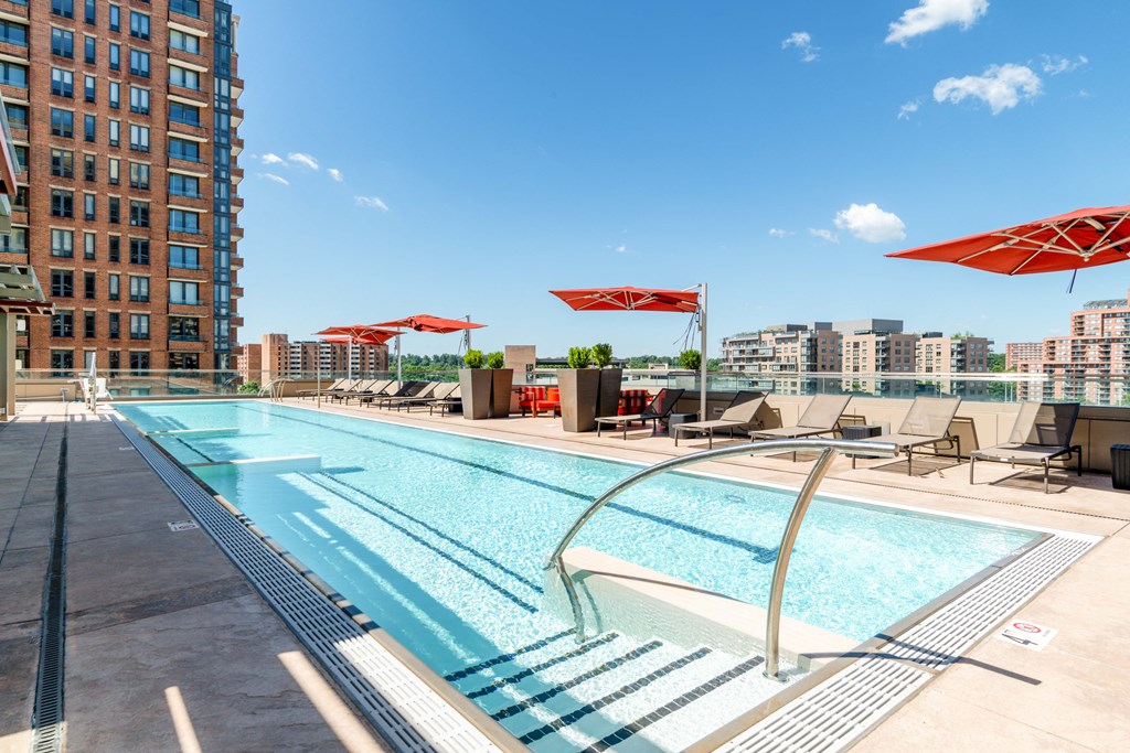 a swimming pool with chairs and umbrellas on a sunny day at a hotel