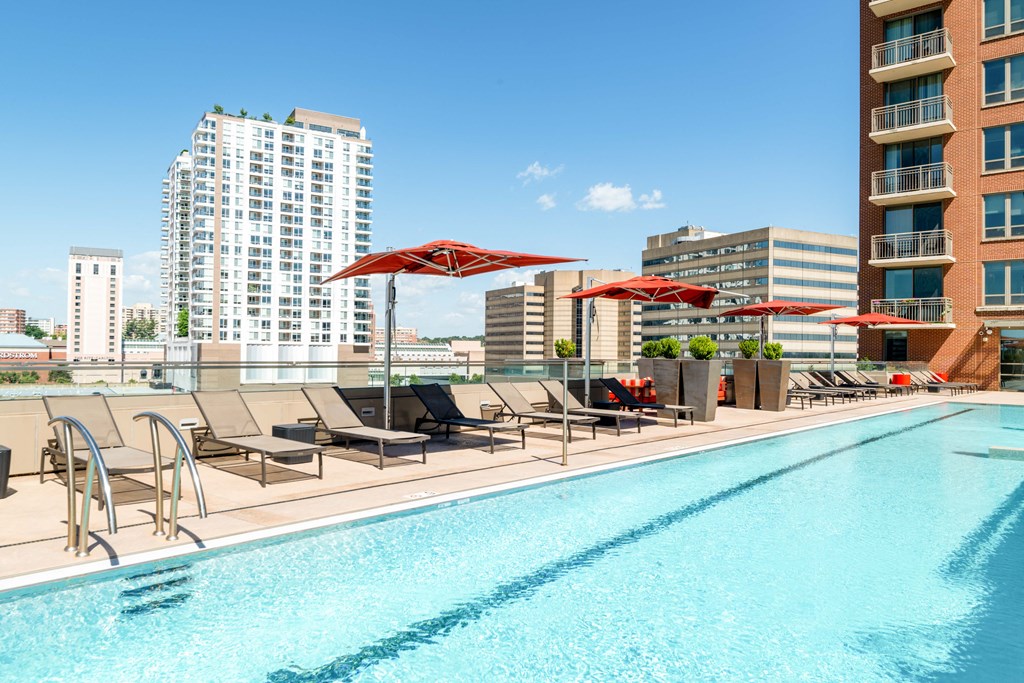 a swimming pool with chairs and umbrellas on top of a building