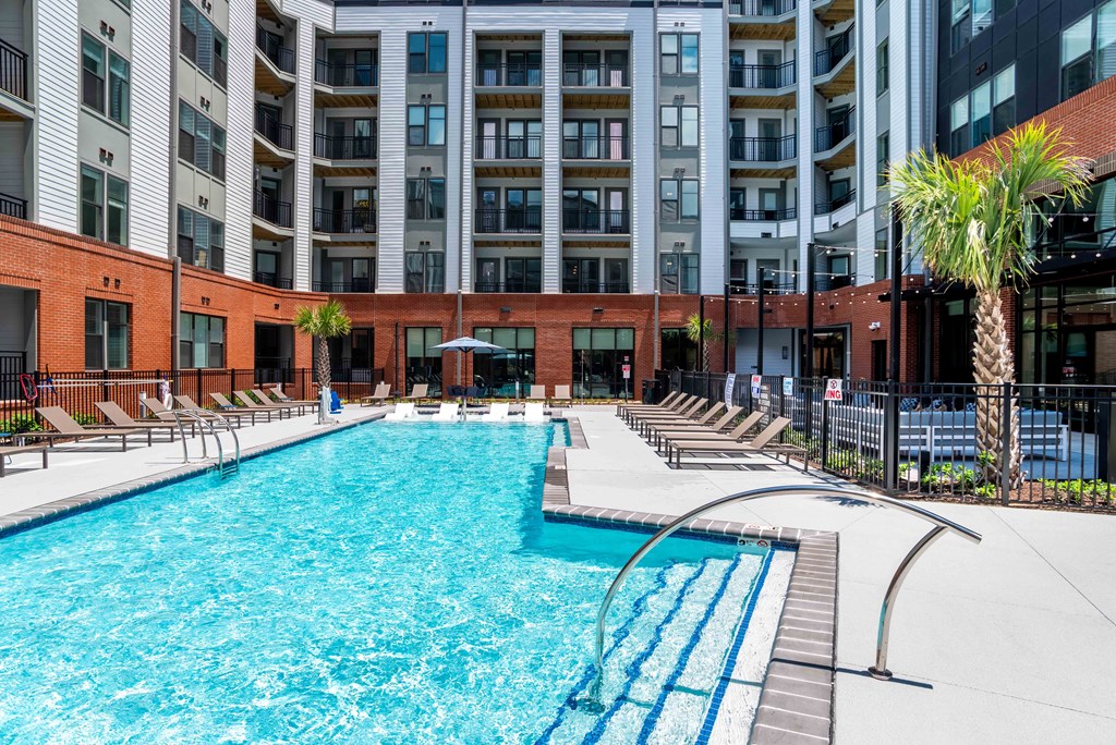 a swimming pool with chairs and a building in the background at Metropolitan at the Riverwalk, Wilmington, North Carolina