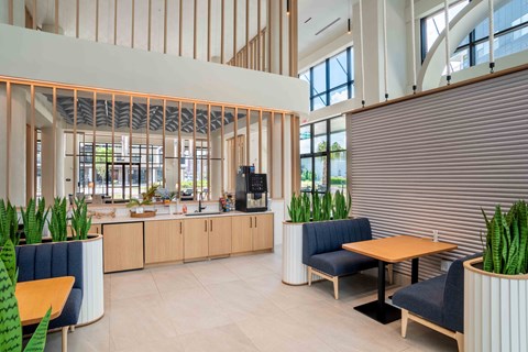 the lobby of a hotel with a kitchen and tables and chairs
