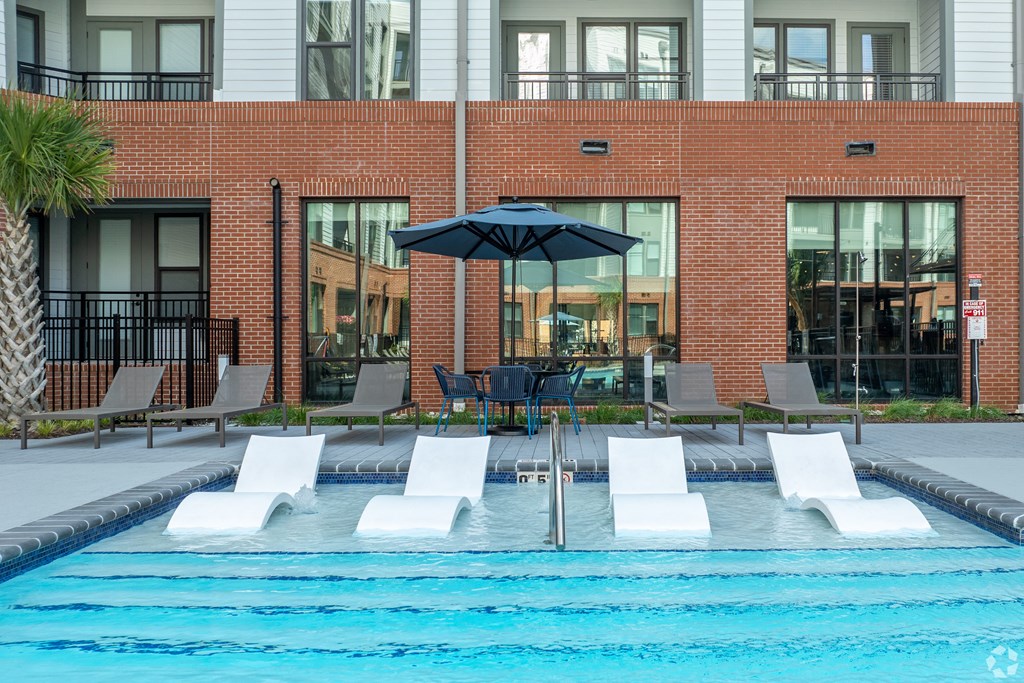 a swimming pool with lounge chairs and an umbrella in front of a buildingat Metropolitan at the Riverwalk, North Carolina
