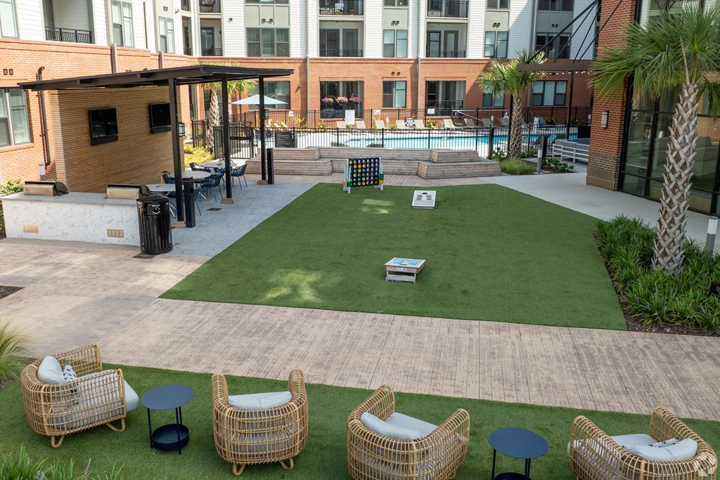 a grassy area with chairs and a pool with a building in the background
