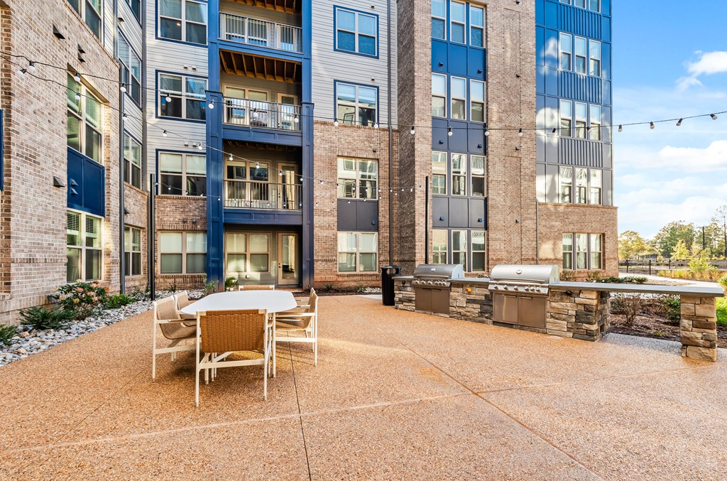 A patio area with a table and chairs in front of a multi-story building.