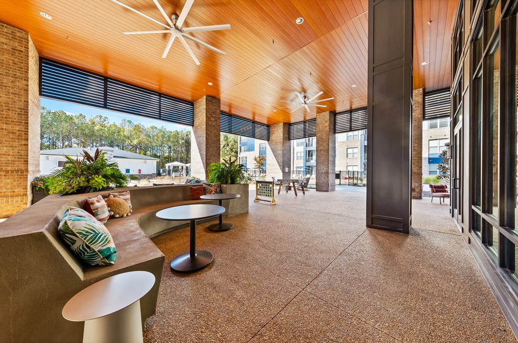 A modern outdoor seating area with a wooden ceiling and concrete flooring