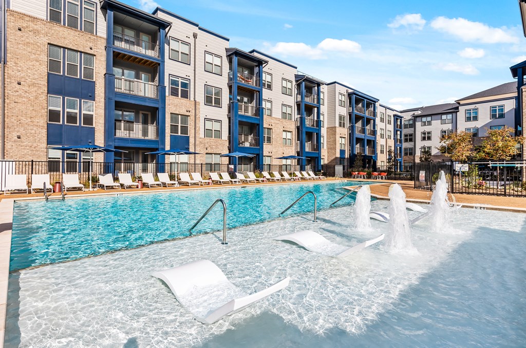 A pool with a fountain and lounge chairs at Preston Ridge Cary, NC.