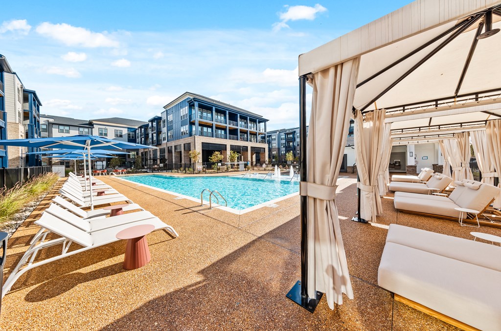 A pool area with sun loungers and a cabanas at Preston Ridge Apartments in Cary, NC.