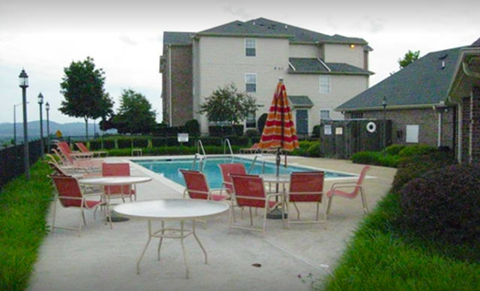 a pool with chairs and tables and a house in the background