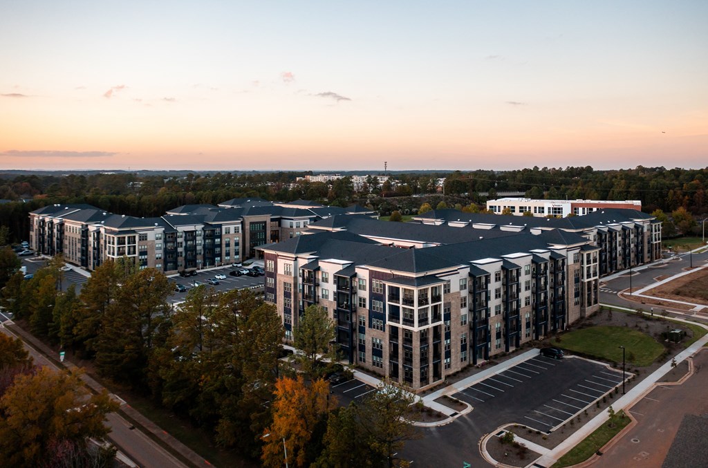 A large, modern building complex with a parking lot in front.