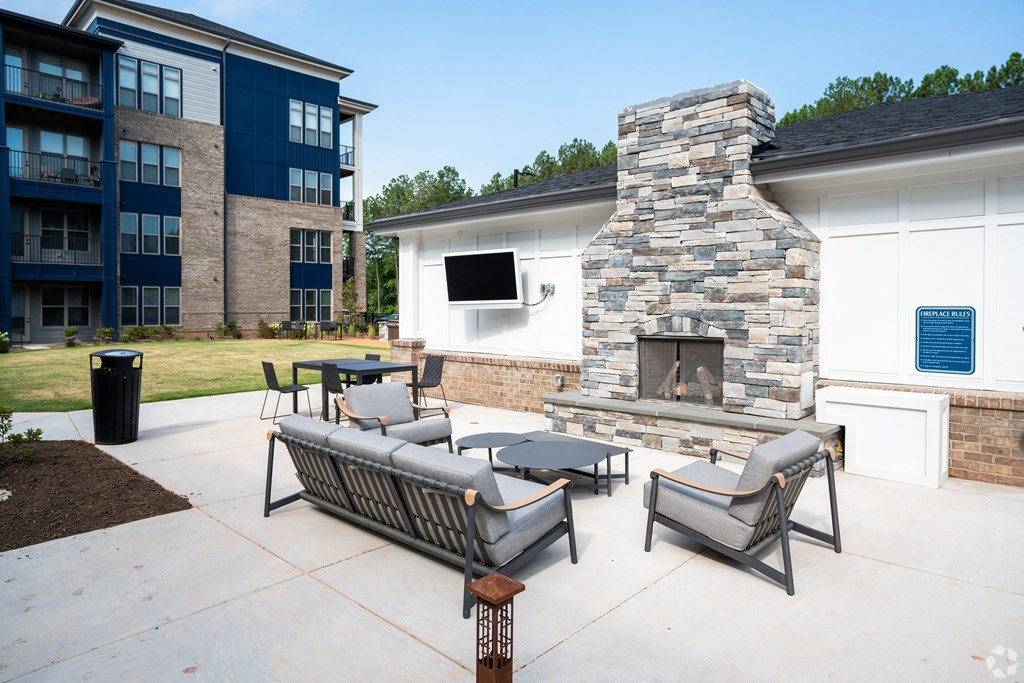 an outdoor patio with furniture and a stone fireplace at Preston Ridge, Cary, 27513