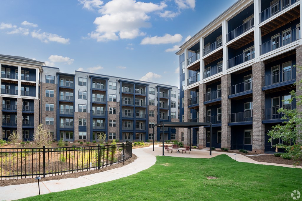an exterior view of an apartment building with green grass and a walkway at Preston Ridge Cary, NC