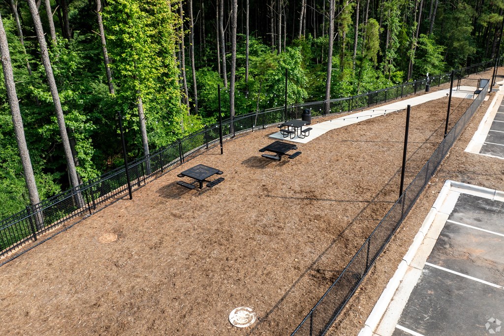 a fenced in dog park with benches and trees at Preston Ridge Apartments Cary, NC