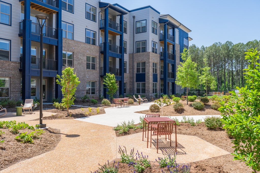 an outdoor area with a table and chairs in front of an apartment building at Preston Ridge, North Carolina