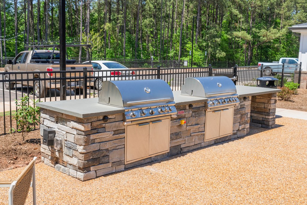 an outdoor kitchen with two grills next to a fence at Preston Ridge, Cary