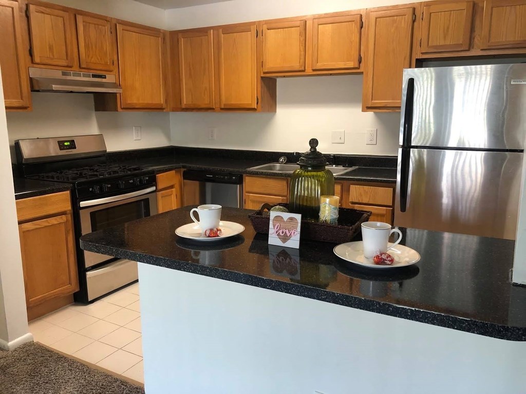 A kitchen with wooden cabinets and a black countertop at Shenandoah Station Apartments, Virginia