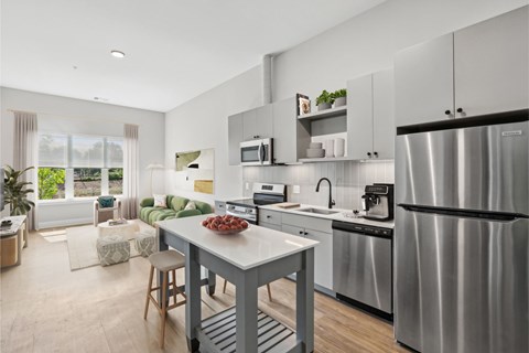 A modern kitchen with stainless steel appliances and a dining table set with a bowl of fruit.