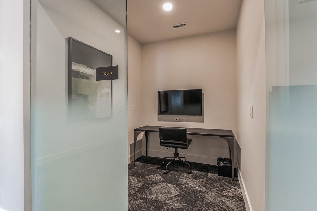 an office with a desk and a tv in a room with a glass door at South and Hollis, North Carolina