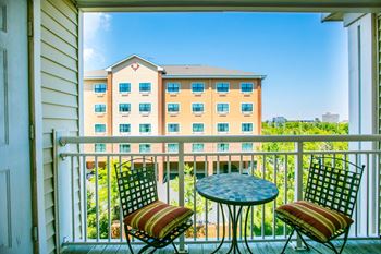 a balcony with two chairs and a table and a building in the background