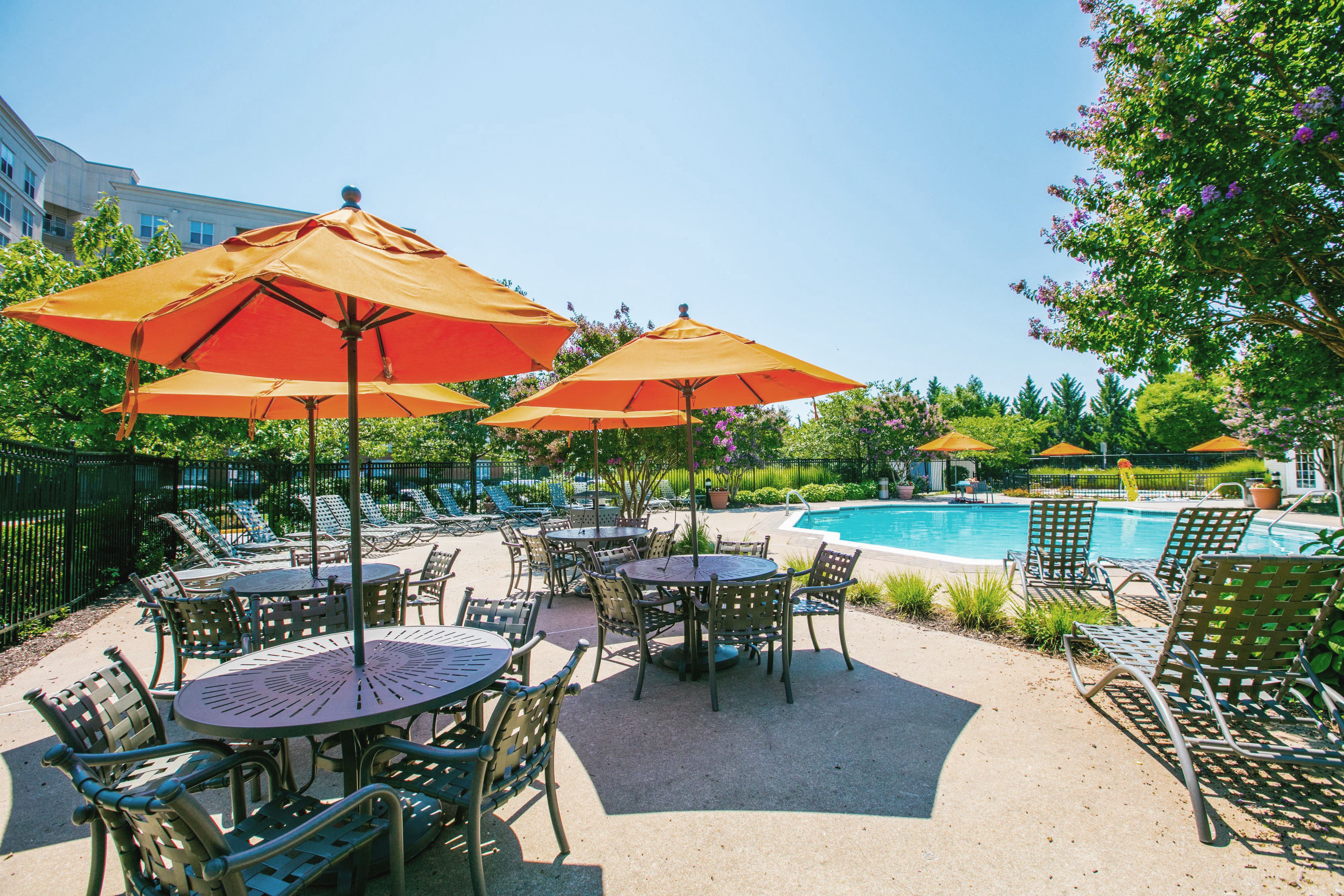 a patio with tables and umbrellas next to a swimming pool at Springfield Crossing, Springfield, VA, 22150