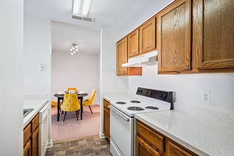 a kitchen with white appliances and wooden cabinets and a dining room with yellow chairs