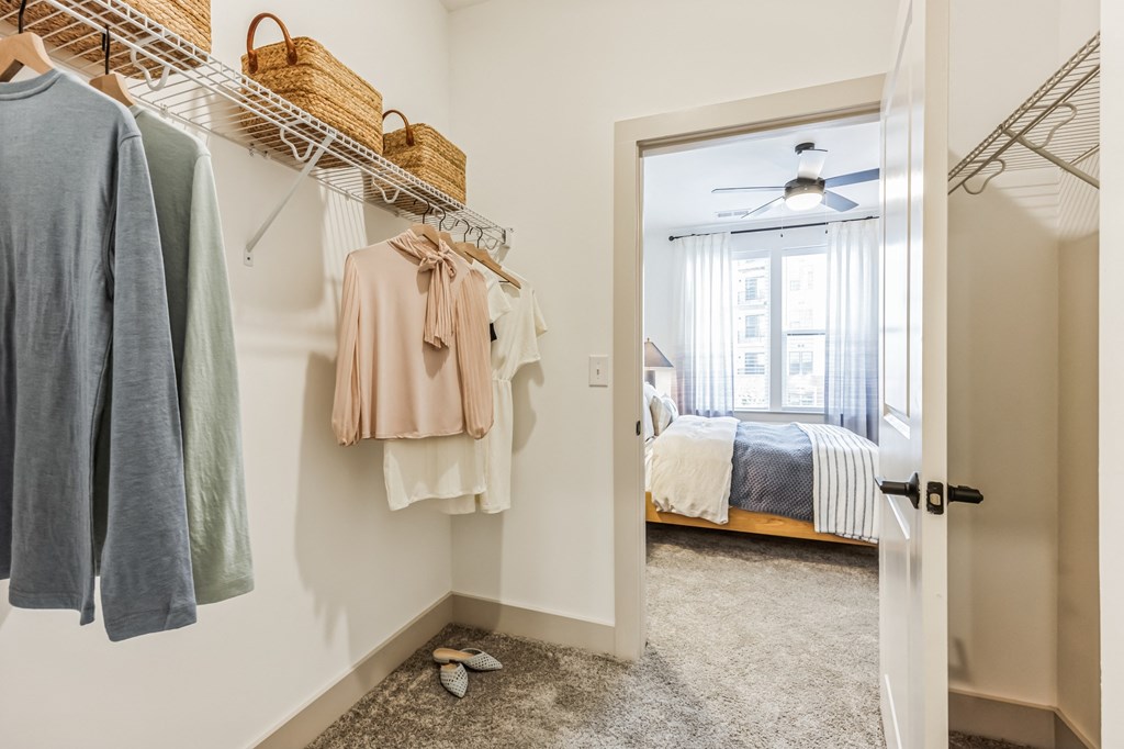 a walk in closet with clothes hanging on a rack and a door to a bedroom at Metropolitan at the Riverwalk, Wilmington, NC 28401