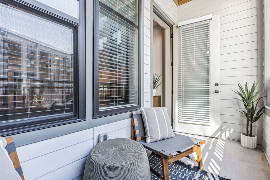a small porch with a chair and a table and windows at Metropolitan at the Riverwalk, Wilmington North Carolina