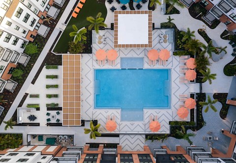 A swimming pool surrounded by orange chairs and a white table.