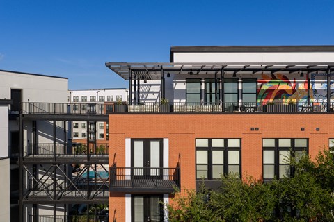 A red brick building with a balcony and a mural on the side.