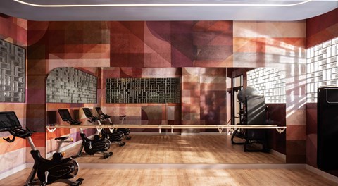 A gym with a row of stationary bikes and a row of treadmills at The Stevedore Apartments in Tampa, FL 33605
