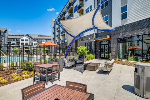 A patio area with a table and chairs and a pool in the background.