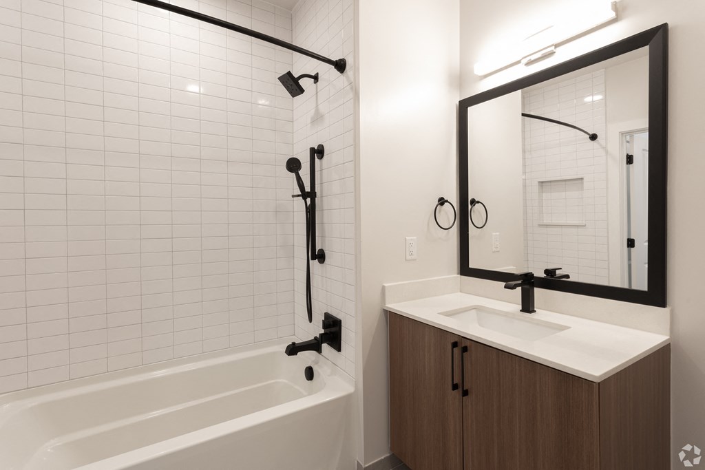 a bathroom with a white tub and a sink and a mirror