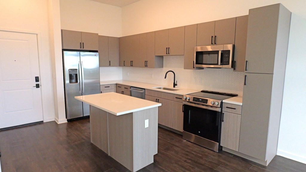 an empty kitchen with stainless steel appliances and white counter tops