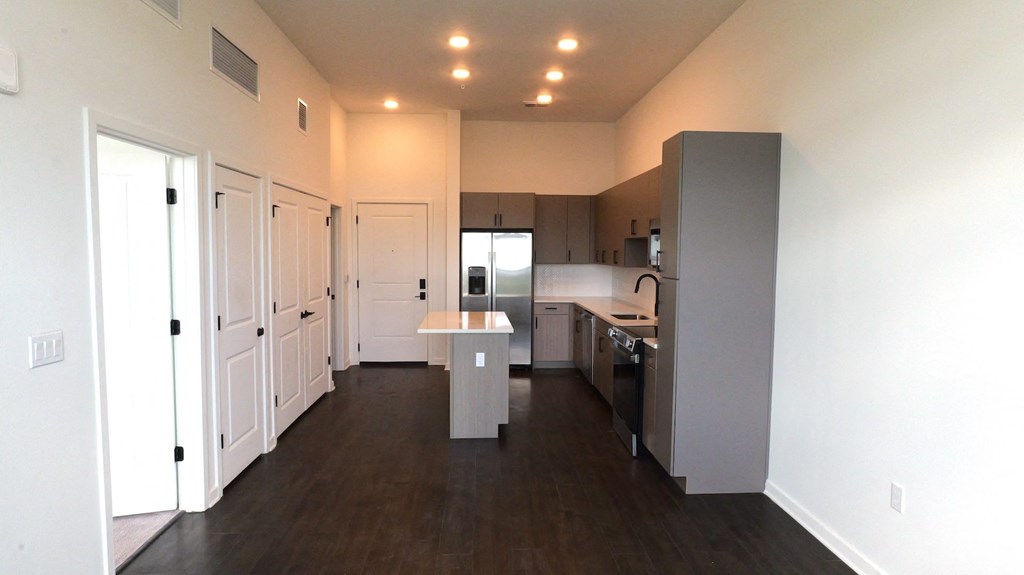 an empty kitchen with white cabinets and a stainless steel refrigerator