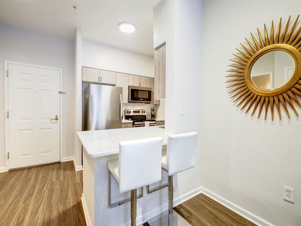 a white kitchen with a white counter top and a stainless steel refrigerator at Lincoln Old Town, Alexandria Virginia