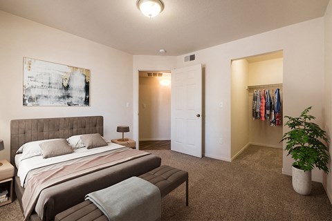 A bedroom with a bed, a bench, and a plant at West Park Apartments, Albuquerque, 87114