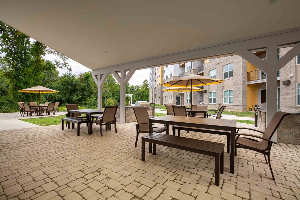 a covered patio with tables and chairs and umbrellas at Woodmore Grand, Bowie