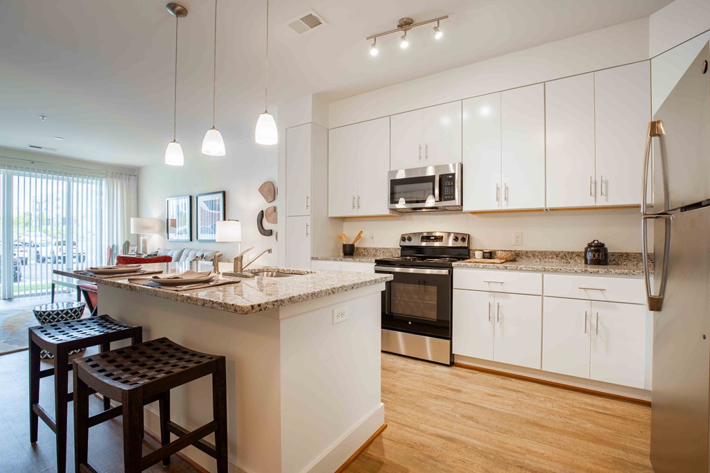 Kitchen a kitchen with white cabinets and a large island with granite countertops at Woodmore Grand, Bowie, 20721
