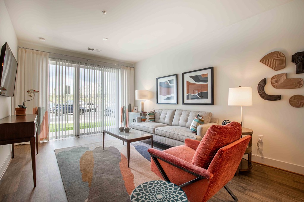 a living room with a couch and a chair and a window at Woodmore Grand, Bowie
