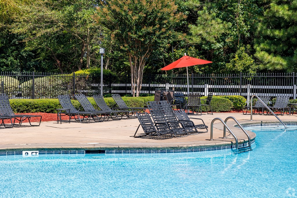 a swimming pool with lounge chairs and an umbrella at Alexander Ridge Apartments, Georgia