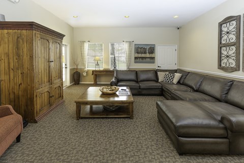 A living room with a brown leather couch and a wooden cabinet.