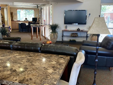 A living room with a black leather couch and a television on the wall.